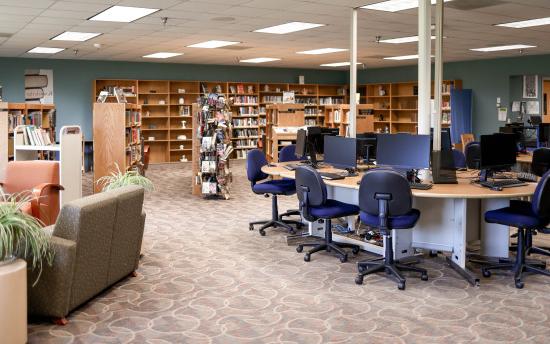 A photo of the library featuring a table full of desktop computers and many bookshelves